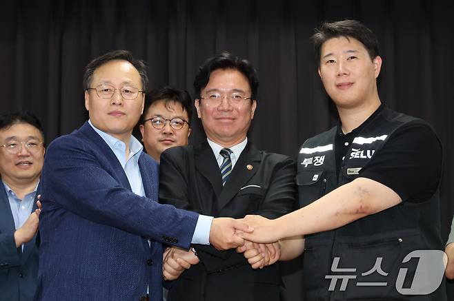 20일 경기 수원시 장안구 경기고용노동청에서 열린 삼성전자 임금협상을 마친 후 여명구 삼성전자 DS(디바이스솔루션·반도체 사업 담당) 피플팀장(왼쪽부터)과 김영훈 고용노동부 장관, 최승호 삼성그룹 초기업노동조합 삼성전자지부 위원장이 잠정 합의한에 서명한 후 손을 맞잡고  있다. 2026.5.20 ⓒ 뉴스1 김영운 기자