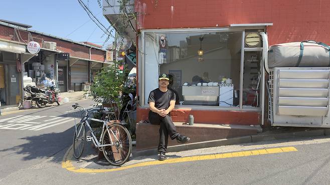 Park Sang-jun, the owner of cafe Elak, poses in front of his shop [WOO JI-WON]