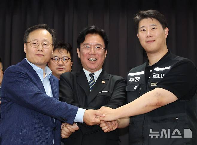 [수원=뉴시스] 김종택기자 = 지난 20일 경기 수원시 장안구 경기고용노동청에서 열린 삼성전자 임금협상을 마친 후 여명구 삼성전자 DS(디바이스솔루션·반도체 사업 담당) 피플팀장(왼쪽부터)과 김영훈 고용노동부 장관, 최승호 삼성그룹 초기업노동조합 삼성전자지부 위원장이 잠정 합의한에 서명한 후 손을 맞잡고 파이팅을 외치고 있다. (공동취재) 2026.05.20. photo@newsis.com
