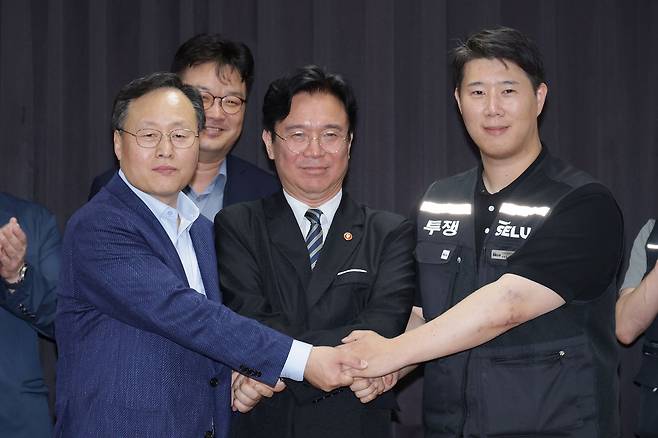 20일 경기도 수원시 장안구 경기고용노동청에서 열린 삼성전자 임금협상을 마친 후 여명구 삼성전자 DS(디바이스솔루션) 피플팀장과 김영훈 고용노동부 장관, 최승호 삼성그룹 초기업노동조합 삼성전자지부 위원장이 잠정 합의한에 서명한 후 손을 맞잡고 있다. 김성룡 기자