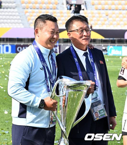 [OSEN=수원, 이대선 기자] 우승컵도, 100만 달러(약 15억 원) 우승 상금도 북한 내고향여자축구단 차지가 됐다. 논란 속 한국에서 열린 결승전에서 내고향은 일본 도쿄 베르디 벨레자를 꺾고 아시아 정상에 올랐다. 경기장 분위기 역시 마지막까지 씁쓸함을 남겼다.내고향은 23일 오후 수원종합운동장에서 열린 2025-2026 아시아축구연맹(AFC) 여자 챔피언스리그(AWCL) 결승전에서 도쿄 베르디를 1-0으로 꺾고 우승을 차지했다. 이날 공식 관중은 2670명이었다.경기 종료 후 내고향여자축구단 리유일 감독, 현철윤 단장이 기념촬영을 하고 있다. 2026.05.23 /sunday@osen.co.kr