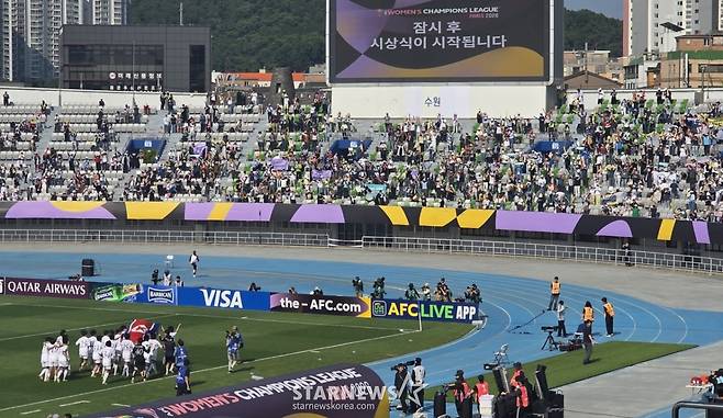 북한 내고향축구선수단(왼쪽 하단)이 23일 수원종합운동장에서 열린 2025-2026 아시아축구연맹(AFC) 여자 챔피언스리그 우승 직후 인공기를 들고 경기장을 돌고 있다. 그런 내고향 선수단을 기립박수와 함성으로 맞이하고 있는 공동 응원단의 모습. /사진=김명석 기자