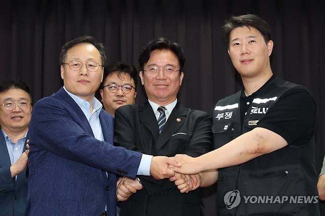 20일 경기도 수원시 장안구 경기고용노동청에서 열린 삼성전자 임금협상을 마친 후 여명구 삼성전자 DS(디바이스솔루션·반도체 사업 담당) 피플팀장과 최승호 삼성그룹 초기업노동조합 삼성전자지부 위원장이 잠정 합의안에 서명한 후 김영훈 고용노동부 장관과 손을 맞잡고 있다. 사진=연합뉴스 제공