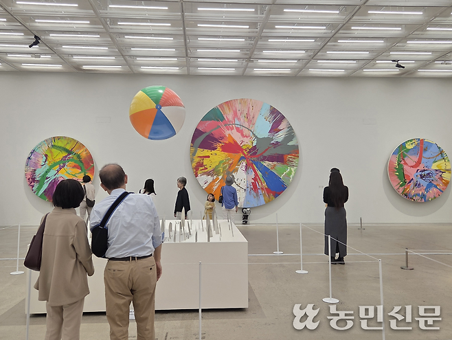 데이미언 허스트의 스핀 페인팅 연작 ‘아름답게 폭발하는 막무가내 대혼란과 광기 무지개의 소용돌이 그리고 죽음의 화산 페인팅(1999)’을 관람하는 모습.