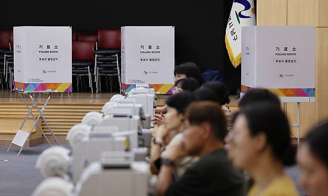 6·3 지방선거 사전투표를 하루 앞둔 28일 울산시 남구청 대강당에 마련된 사전투표소에 투표사무원들이 모의 투표를 하며 장비를 점검하고 있다. 연합뉴스