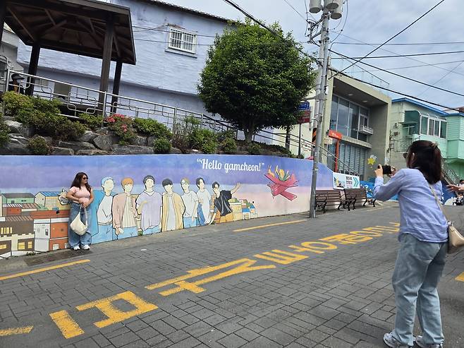Tourists take a picture with a BTS mural at Gamcheon Culture Village in Busan on May 26. [JIN EUN-SOO]