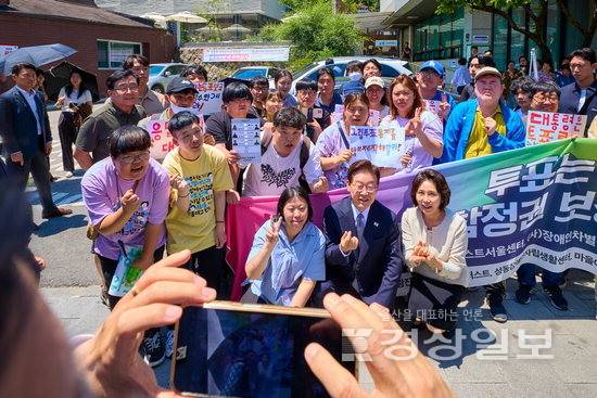 ▲ 이재명 대통령과 김혜경 여사가 제9회 전국동시지방선거 사전투표 첫날인 지난달 29일 서울 종로구 삼청동 주민센터 사전투표소 앞에서 발달장애인 참정권 보장 촉구 장애인단체 관계자들의 의견을 청취한 뒤 함께 기념 촬영을 하고 있다. 연합뉴스