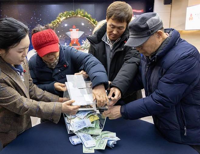 인천의 쪽방촌인 동구 괭이부리마을 주민 대표 권영자(왼쪽 두 번째)씨와 무료급식소 이용자 대표 이동승(네 번째)씨 등이 1월 27일 서울 중구 사랑의열매회관에서 사랑의열매 사회복지공동모금회에 성금을 전달하고 있다. 모금회 제공