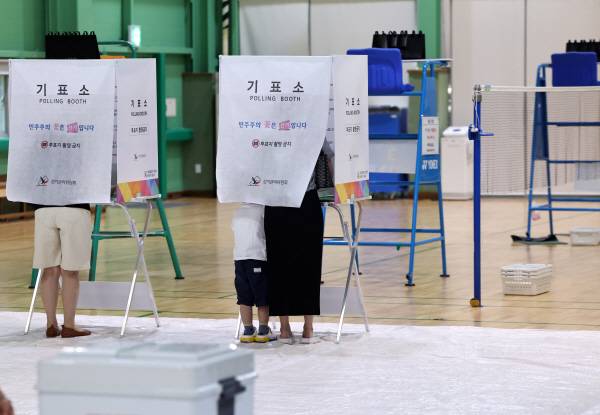 제9회 전국동시지방선거일인 3일 서울 매봉산실내배드민턴장에 마련된 도곡1동 제5투표소에서 아이를 동반한 유권자가 투표를 하고 있다. 연합뉴스