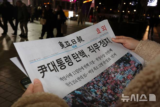 [서울=뉴시스] 홍효식 기자 = 사진은 2024년 12월14일 오후 서울 종로구 광화문역 일대에 한 시민이 윤석열 전 대통령 탄핵 가결 관련 호외를 읽고 있는 모습. 2024.12.14. yesphoto@newsis.com