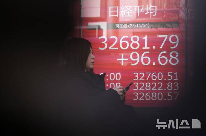 [도쿄=AP/뉴시스] 인공지능(AI) 투자 열풍이 미국을 넘어 아시아 증시까지 밀어 올리고 있다. 사진은 2023년 11월14일 일본 도쿄의 한 증권사 앞에서 한 시민이 닛케이225지수가 표시된 전광판 앞을 지나가고 있는 모습. 2026.06.03.