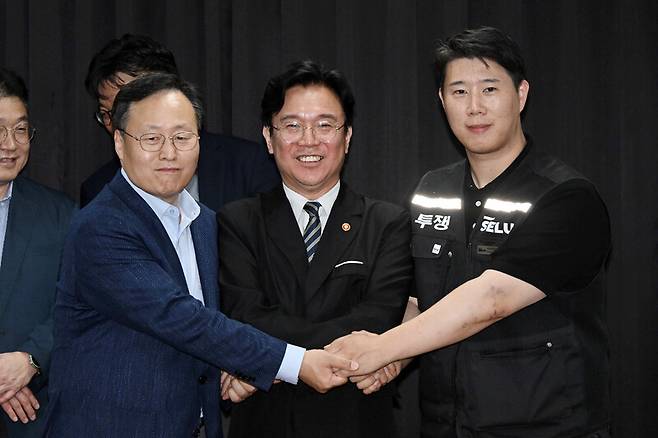 지난달 20일 경기도 수원시 장안구 경기지방고용노동청에서 김영훈 고용노동부 장관(앞줄 가운데), 최승호 삼성전자 노조 공동투쟁본부 위원장(맨 오른쪽), 여명구 디에스(DS·디바이스솔루션, 반도체 사업 담당) 피플팀장이 손을 맞잡고 있다. 성과급 배분 방식을 두고 갈등을 빚어온 삼성전자 노사는 이날 합의를 이뤄냈다. 공동취재사진