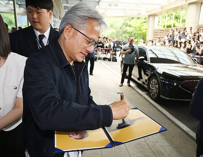 엔비디아 젠슨 황 최고경영자(CEO)가 5일 전용기편으로 서울 강서구 김포비즈니스항공센터(SGBAC)에 도착해 센터를 나서며 팬들에게 사인을 해주고 있다.(사진=연합뉴스)