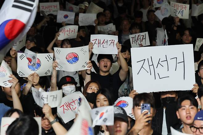 6일 새벽 서울 송파구 올림픽공원 핸드볼경기장 앞에서 시민들이 태극기와 ‘재선거’라고 적힌 손팻말을 들고 선거 관리 부실에 항의하고 있다. 이들은 투표용지 부족 사태와 개표 과정에 대한 문제 제기를 하며 경기장 주변에 모였다. / 고운호 기자