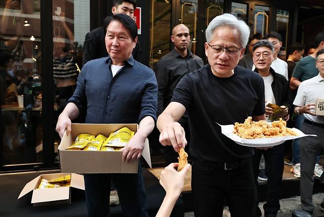 젠슨 황 엔비디아 최고경영자(CEO)와 최태원 SK 회장이 7일 서울 강남구 깐부치킨 삼성점에서 치맥 회동을 하던 중 HBM 칩과 치킨을 나눠주고 있다. 연합뉴스