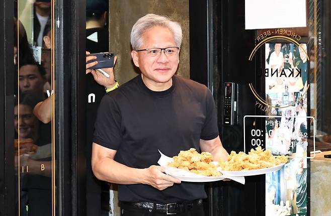 젠슨 황 엔비디아 최고경영자(CEO)가 7일 서울 강남구 깐부치킨 삼성점에서 치맥 회동을 하던 중 치킨을 들고 나오고 있다. 연합뉴스