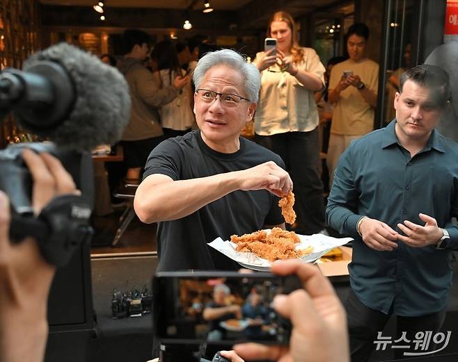 젠슨 황 엔비디아 최고경영자(CEO)와 최태원 SK 회장이 7일 서울 강남구 깐부치킨에서 열린 '치맥 회동'중 밖으로 나와 취재진에게 음식을 나눠주고 있다. 사진=이수길 기자
