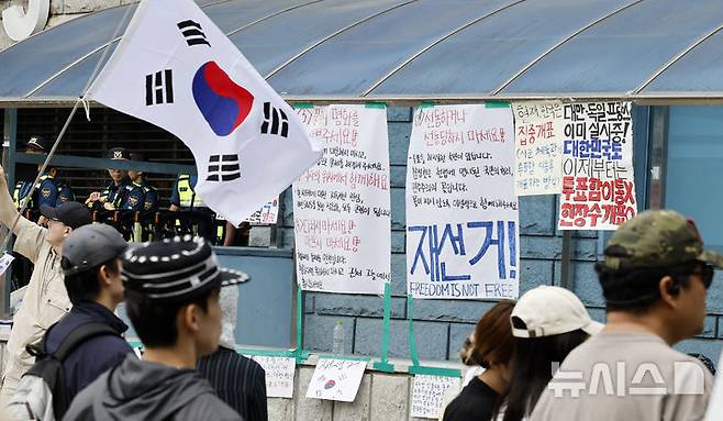 [서울=뉴시스] 김혜진 기자 = 제9회 전국동시지방선거 투표용지 부족 사태에 항의하며 개표소 봉쇄 시위를 이어가는 시민들이 8일 서울 송파구 올림픽공원 핸드볼경기장에 설치된 개표소 앞에서 재선거를 요구하고 있다. 2026.06.08. jini@newsis.com