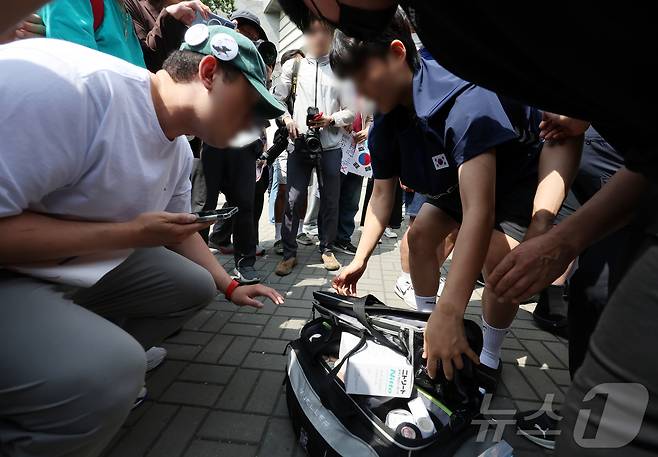 제9회 전국동시지방선거 투표용지 부족 사태를 규탄하는 집회가 계속되고 있는 8일 재선거를 요구하는 시민들이 서울 송파구 올림픽공원 핸드볼경기장을 나온 핸드볼 주니어 대표팀 관계자의 물품을 확인하고 있다. 2026.6.8 ⓒ 뉴스1 김진환 기자
