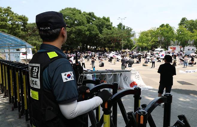 6·3 지방선거 투표용지 부족 사태를 규탄하며 재선거를 요구하는 '잠실 개표소 봉쇄 시위'가 계속되고 있는 9일 서울 송파구 올림픽공원 핸드볼경기장 출입구 앞에서 한 경찰이 집회를 지켜보고 있다.(사진= 연합뉴스)