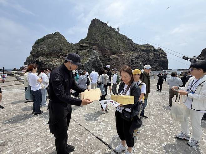[울릉=뉴시스]독도지킴이학교 독도 탐방에 참여한 정수경 부천수주초 교사가 독도 경비대에 학생들 편지를 전달하고 있다. (사진 = 동북아역사재단) 2026.06.09. photo@newsis.com *재판매 및 DB 금지