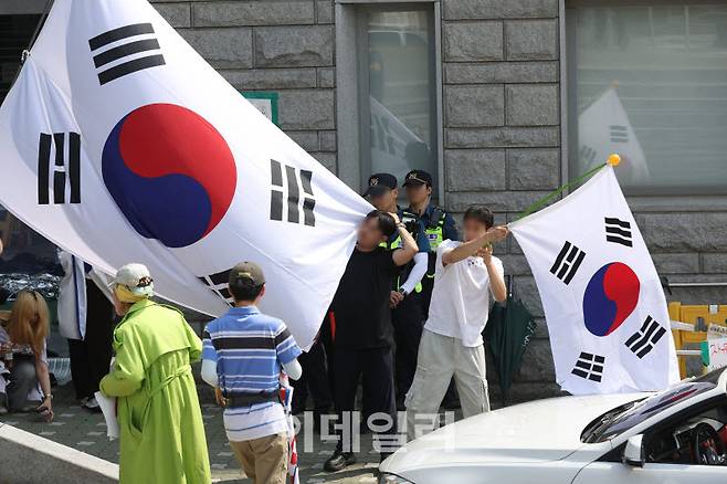 6·3 지방선거 투표용지 부족 사태로 빚어진 '잠실 개표소 봉쇄 시위'가 7일째 이어지고 있는 11일 서울 송파구 올림픽공원 핸드볼경기장에서 부정선거 시위 참석자들이 태극기로 시야를 가리는 등 경찰들의 경계 업무를 방해하고 있다.(사진=이영훈 기자)