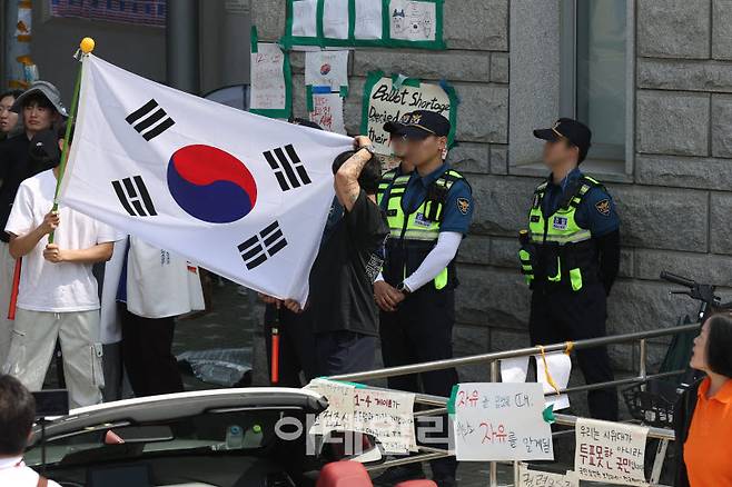 6·3 지방선거 투표용지 부족 사태로 빚어진 '잠실 개표소 봉쇄 시위'가 7일째 이어지고 있는 11일 서울 송파구 올림픽공원 핸드볼경기장에서 부정선거 시위 참석자들이 태극기로 시야를 가리는 등 경찰들의 경계 업무를 방해하고 있다.(사진=이영훈 기자)