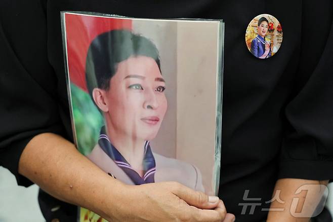 12일(현지시간) 태국 방콕의 쭐랄롱꼰 기념 병원 밖에서 한 사람이 이날 사망한 랏차사리니시리팟 공여 파차라키티야파 공주의 사진을 들고 그의 모습이 담긴 배지를 달고 있다. 2026.06.12 ⓒ 로이터=뉴스1