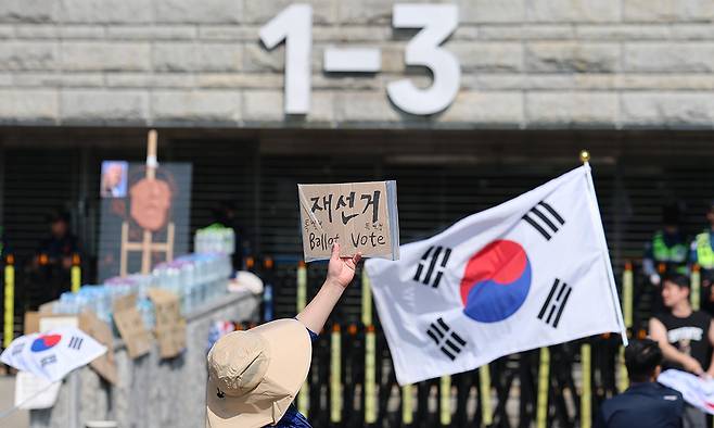 제9회 전국동시지방선거 투표용지 부족 사태를 규탄하는 개표소 봉쇄 시위가 계속된 11일 서울 송파구 올림픽공원 핸드볼경기장 앞에서 시위대가 재선거를 요구하는 피켓을 들고 있다. 뉴스1