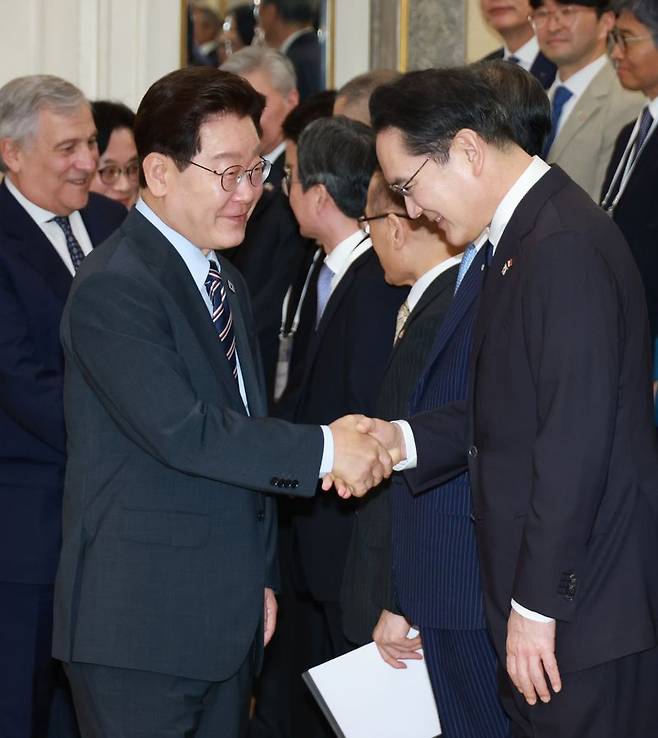 이재명 대통령이 12일(현지시간) 이탈리아 로마의 한 호텔에서 열린 비즈니스 라운드테이블에 입장하며 이재용 삼성전자 회장과 악수하고 있다. 연합뉴스