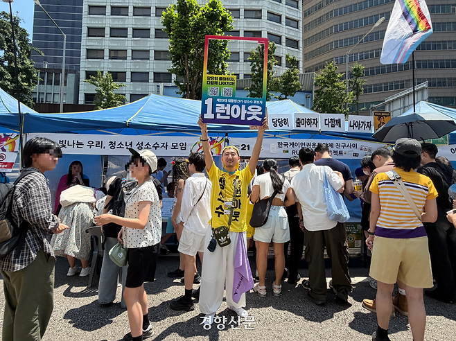 제27회 서울퀴어문화축제에서 ‘런아웃’ 부스를 운영하는 참가자가 피켓을 들어 보이고 있다. 김은송 기자