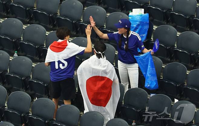 관중석을 청소하는 일본 팬들 ⓒ 로이터=뉴스1