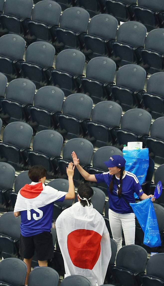 경기가 끝난 뒤 관중석에 남은 쓰레기를 수거하고 있는 일본 축구팬들.   AP·AFP연합