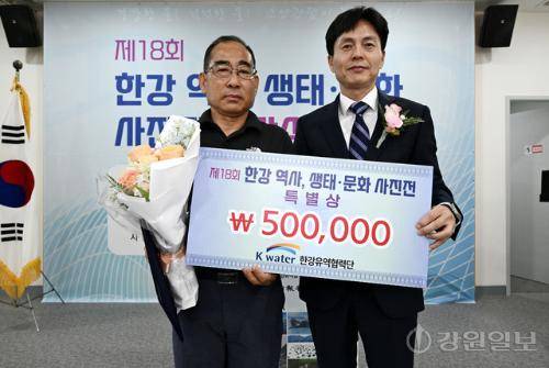 17일 춘천시 소양강댐 물 문화관에서 열린 제18회 한강 역사, 생태·문화 사진공모전 시상식에서 특별상을 수상한 윤기욱씨(왼쪽)가 장진규 한국수자원공사 한강유역협력단장으로부터 축하 꽃다발을 전달받고 기념촬영을 하고 있다. 임도혁기자