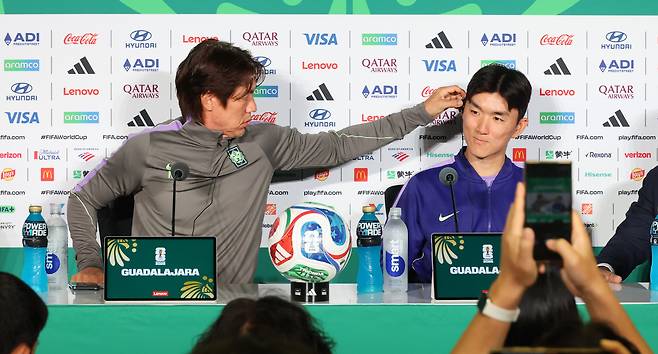 홍명보(왼쪽) 축구 대표팀 감독이 17일(현지 시간) 멕시코 과달라하라 스타디움에서 진행된 멕시코전 공식 기자회견에서 황인범에게 통역기를 끼워주고 있다. 연합뉴스