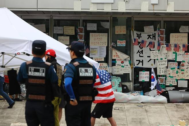 6·3 지방선거 투표용지 부족 사태로 촉발된 개표소 봉쇄 시위가 15일째 이어지고 있는 19일 서울 송파구 올림픽공원 핸드볼경기장 출입구에 부정선거 문구와 성조기 등이 붙어 있다. 뉴시스