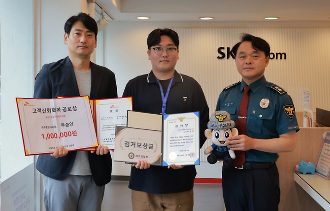 보이스피싱 피해를 예방한 주승인(가운데) SK텔레콤 제주중앙대리점 점장에게 경찰과 SK텔레콤에서 표창 등을 전달하는 모습 (제주경찰청 제공)