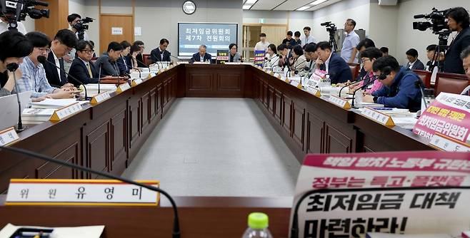 18일 세종시 정부세종청사 최저임금위원회에서 열린 2027년도 최저임금위원회 7차 전원회의에 참석한 사용자위원들과 근로자위원들이 각자의 주장이 적힌 손팻말을 들고 회의를 진행하고 있다. 세종=뉴스1