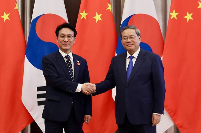 김민석 국무총리(왼쪽)가 23일 중국 다롄 방추도 호텔에서 리창 중국 국무원 총리와 회담하기 전 악수를 하고 있다.  국무총리실 제공