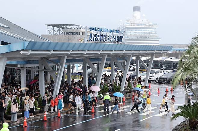 제주도에 호우 특보가 내려진 이달 19일 입국 심사를 밟은 관광객들이 우산을 쓴 채 서귀포강정크루즈터미널을 빠져나오고 있다. 연합뉴스