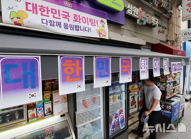 [서울=뉴시스] 조성우 기자 = 2026 북중미 월드컵 거리응원으로 서울 광화문광장 인근 편의점들이 특수를 누렸다. 유통업계에 따르면 한국 대표팀 경기가 열린 지난 19일 서울시 추산 약 1만8000명이 광화문광장에 모이면서 인근 편의점의 얼음·생수·맥주·안주류 등의 매출이 급증했다. 사진은 22일 서울 종로구 광화문광장 인근 편의점에 설치된 월드컵 관련 홍보물.CU는 광화문 인근 10여 개 점포 매출이 전일 대비 약 4배 늘었고, GS25는 138% 증가했다. 세븐일레븐도 광화문 인근 10개 매장의 19일 오전 9시부터 오후 2시까지 매출이 전일 대비 304% 증가했으며, 이마트24는 최대 38% 늘었다. 2026.06.22. xconfind@newsis.com