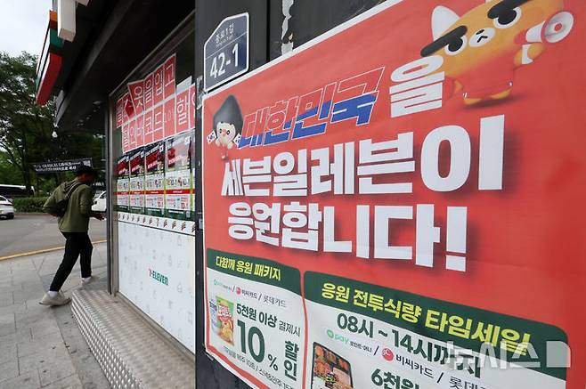 [서울=뉴시스] 조성우 기자 = 2026 북중미 월드컵 거리응원으로 서울 광화문광장 인근 편의점들이 특수를 누렸다. 유통업계에 따르면 한국 대표팀 경기가 열린 지난 19일 서울시 추산 약 1만8000명이 광화문광장에 모이면서 인근 편의점의 얼음·생수·맥주·안주류 등의 매출이 급증했다. 사진은 22일 서울 종로구 광화문광장 인근 편의점에 설치된 월드컵 관련 홍보물.CU는 광화문 인근 10여 개 점포 매출이 전일 대비 약 4배 늘었고, GS25는 138% 증가했다. 세븐일레븐도 광화문 인근 10개 매장의 19일 오전 9시부터 오후 2시까지 매출이 전일 대비 304% 증가했으며, 이마트24는 최대 38% 늘었다. 2026.06.22. xconfind@newsis.com