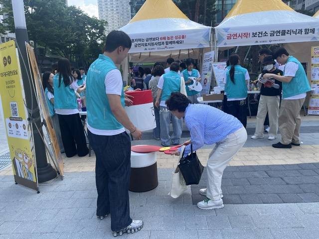 26일 오전 10시30분께 한 시민이 금연 홍보 부스 앞 담배 모형을 가위로 자르고 있다. 김도경 기자