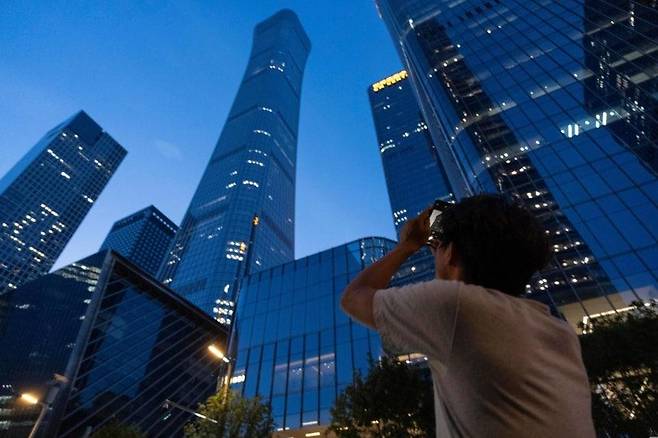중국 베이징에서 26일 한 행인이 마천루 시틱(CITIC)타워의 사진을 찍고 있다. 이날 이 빌딩에 경비행기가 충돌해 1명이 숨지고 13명이 다쳤다. 베이징=AP 연합뉴스