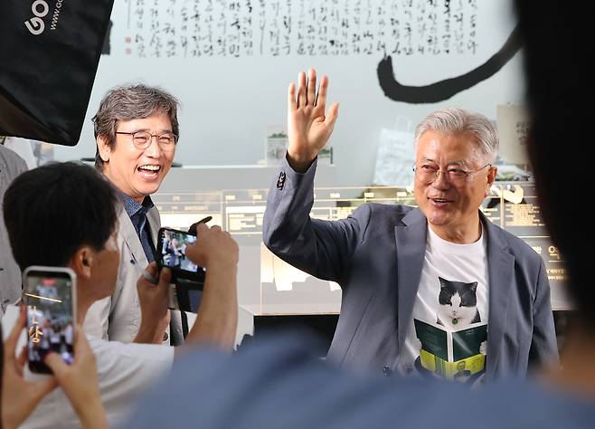 Former President Moon Jae-in, right, and writer Yoo Si-min wave to the audience during a book event at the Pyeongsan Bookstore booth at the Seoul International Book Fair at Coex in Gangnam District, southern Seoul, on June 25. YONHAP
