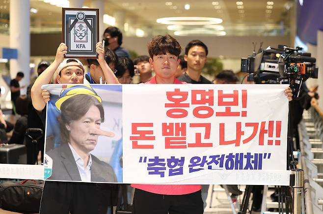 2026 북중미 월드컵 32강 진출에 실패해 한국 축구 국가대표팀에서 사퇴한 홍명보 전 감독이 입국하는 30일 인천국제공항 제2여객터미널을 찾은 팬들이 항의 현수막을 들어올리고 있다. 인천=연합뉴스