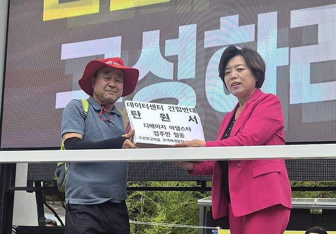 ▲ 과천 주암지구 데이터센터 건립 철회를 요구하는 주민 대표가 2일 과천시청 앞에서 신계용(오른쪽) 시장에게 탄원서를 전달하고 있다. 주민들은 주거지 인접 지역에 데이터센터가 들어선다면 환경 피해가 우려돼 이를 받아들일 수 없다며 강하게 반발하고 있다. /이복한 기자 khan4936@incheonilbo.com