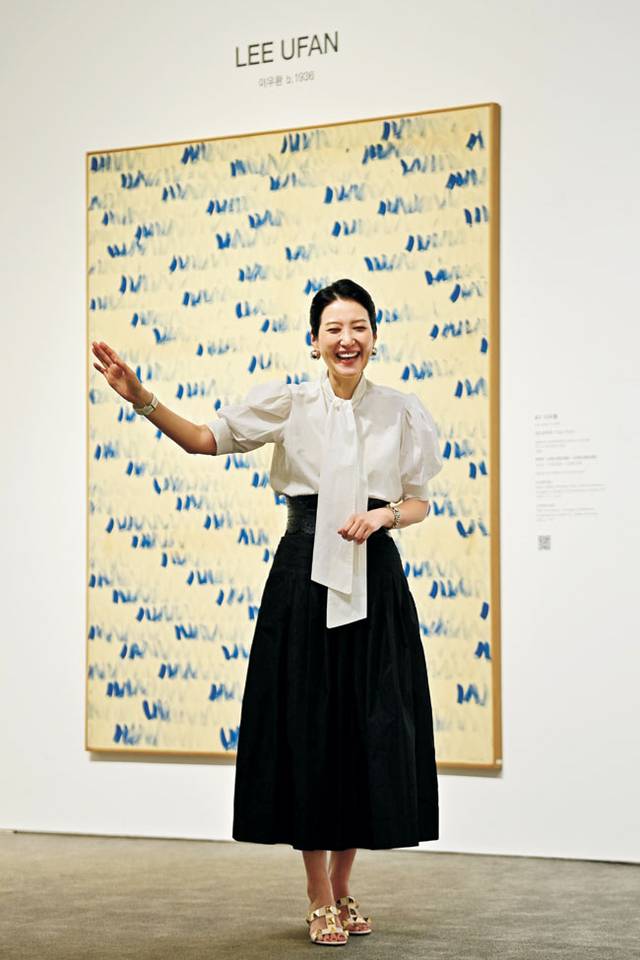 이우환의 ‘점으로부터’(1980) 앞에서 손 이사가 경매 진행 모습을 시연하며 웃고 있다. 이 작품도 15억 원에 팔렸다.  문호남 기자