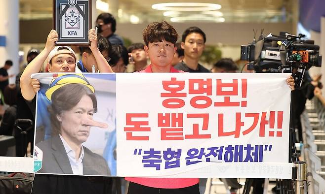 2026 북중미 월드컵 32강 진출에 실패해 한국 축구 국가대표팀에서 사퇴한 홍명보 전 감독이 입국하는 지난달 30일 인천국제공항 제2여객터미널을 찾은 팬들이 항의 현수막을 들어 올리고 있다. 연합뉴스
