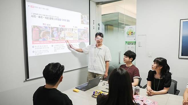 BGF리테일 빅데이터팀 회의에서 김형준 팀장이 해외 SNS와 검색 데이터를 분석한 결과를 설명하고 있다. 빅데이터팀은 자체 AI 크롤링 툴로 바이럴 가능성이 높은 이슈를 찾아 신상품 기획에 반영한다. BGF리테일 제공